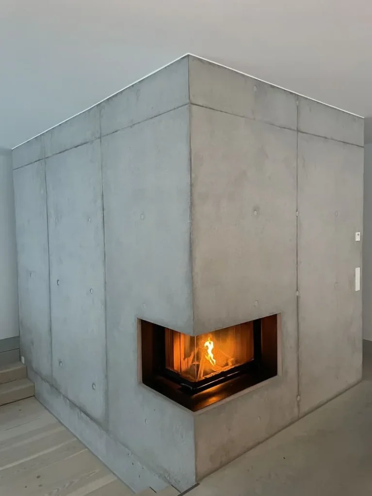 Modernes Eckkamin-Design in massivem Beton mit sichtbarer Flamme, minimalistischer Stil für zeitgenössische Wohnräume.