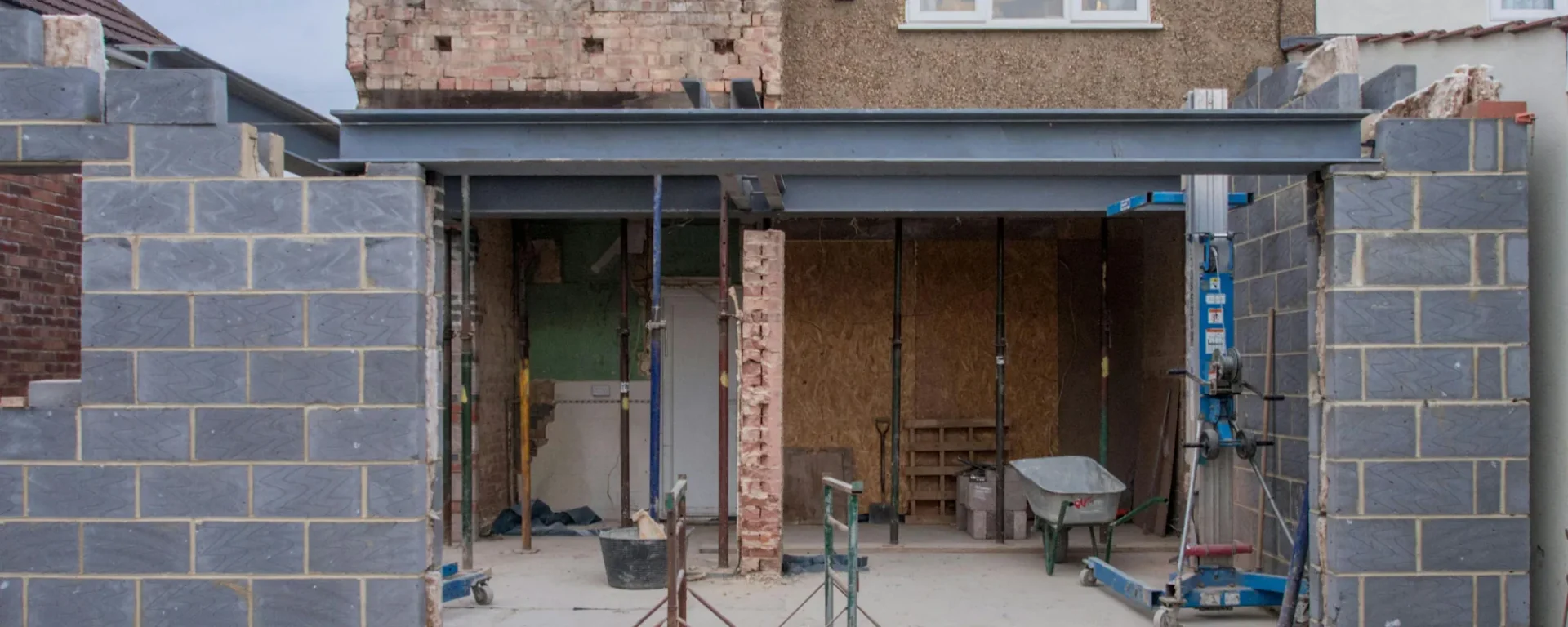 Hausumbau mit neuen Backsteinmauern und Stahlträgern, Baugerüste sichtbar, Baustelle im Aufbau.