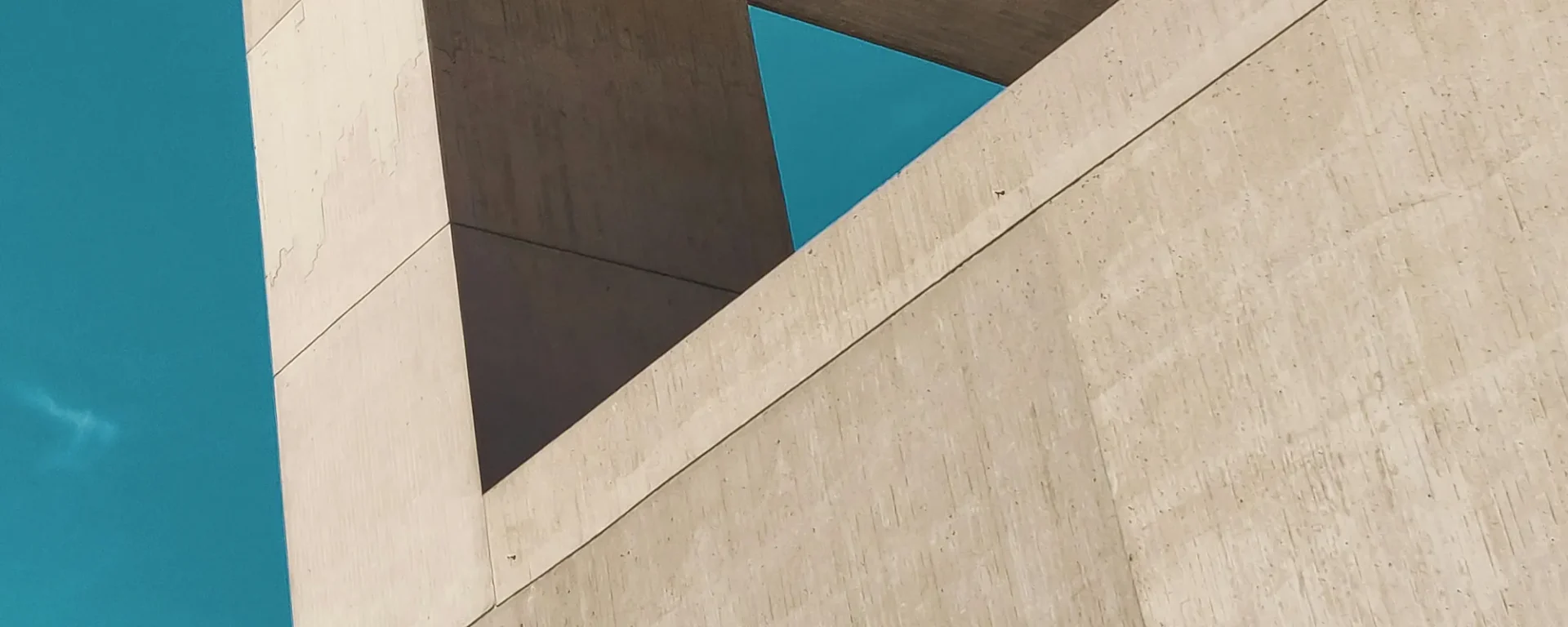 Moderne Architektur, geometrische Strukturen, Betonoberflächen, minimalistisch, blauer Himmel, urbane Baukunst, zeitgenössische Designästhetik.