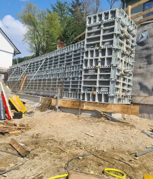 Baustelle mit Schalungsformen und Baumaterialien, umgeben von Vegetation. Ideal für Themen im Bauwesen und Infrastruktur.