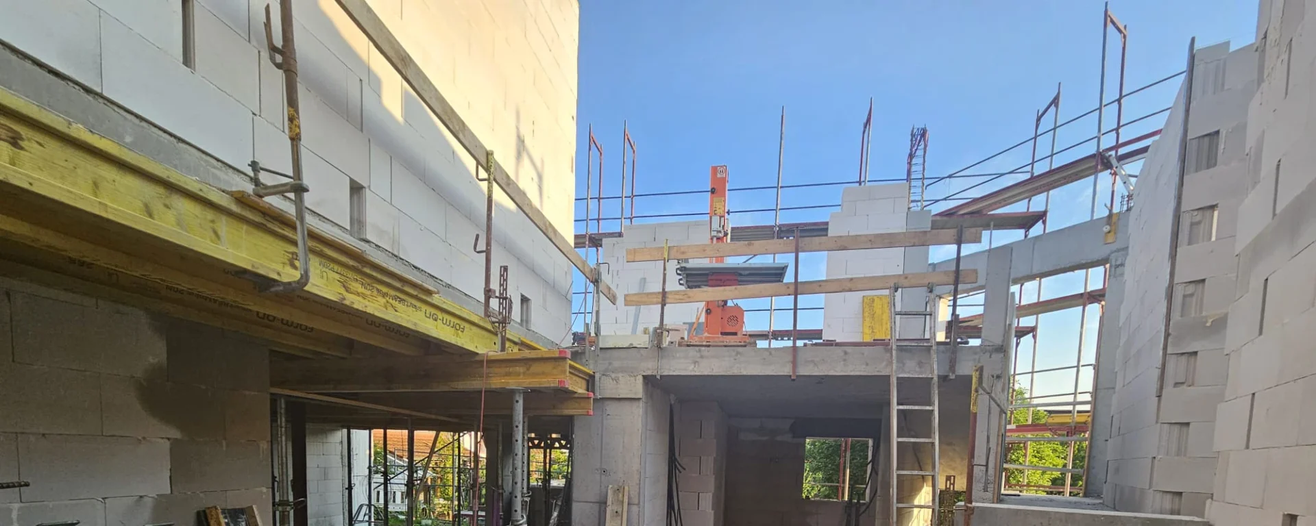 Baustelle mit Rohbau, Gerüst und blauen Himmel; Betonwände und Holzverschalung in moderner Bauweise für Hochbau in Freiburg
